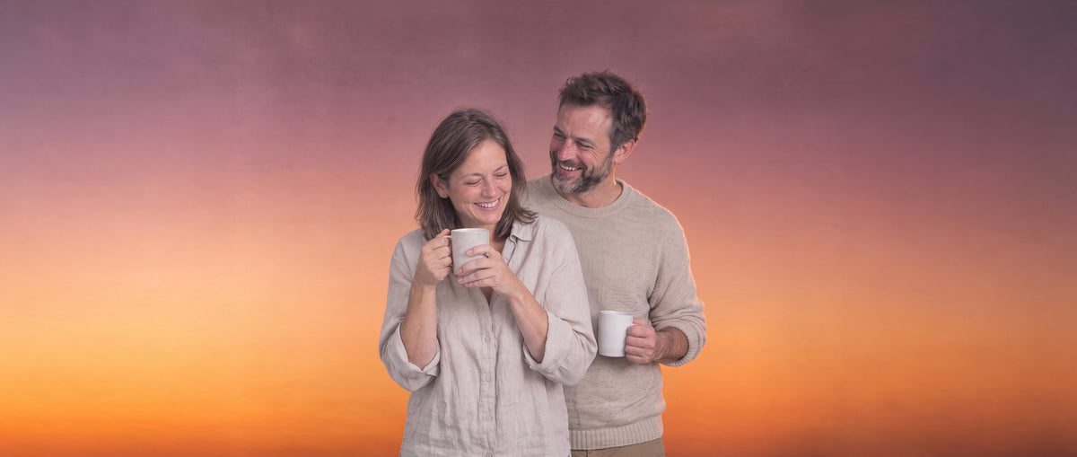 A couple sharing their first coffee of the morning against a sunrise sky