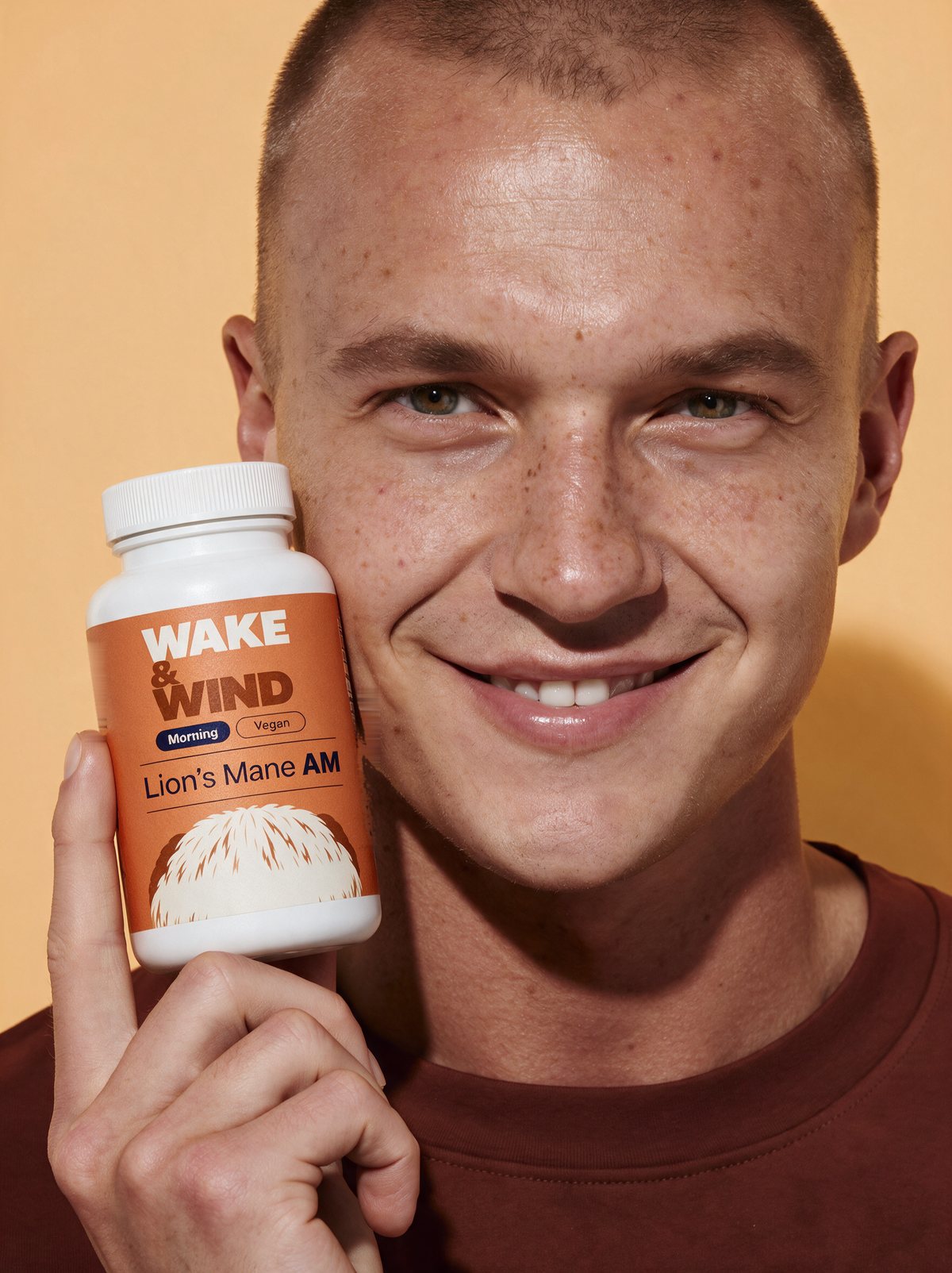 A smiling man holding a Lion's Mane AM lion's mane mushroom capsules bottle beside his face