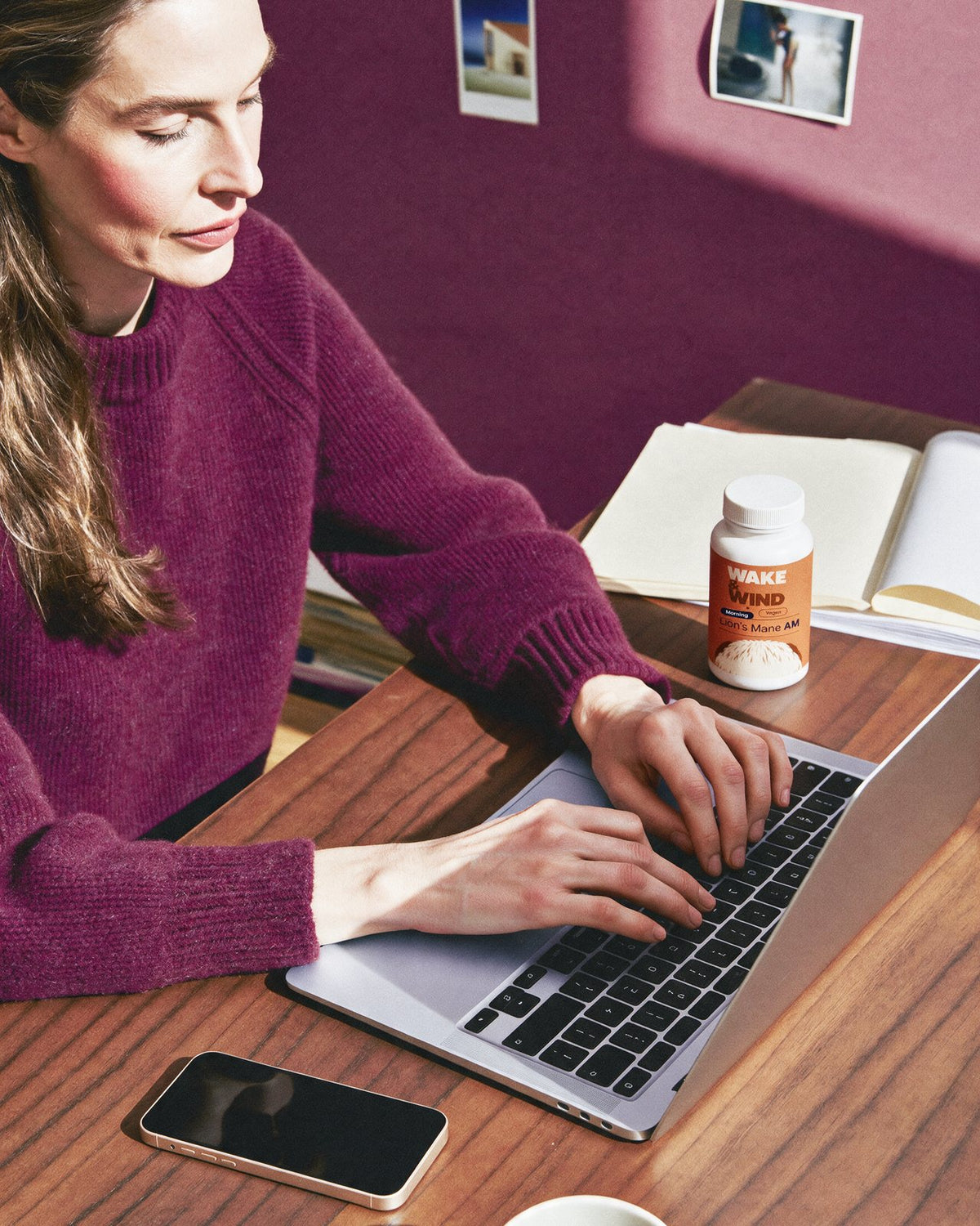 A woman working on a laptop at 08:05 with a Lion's Mane AM bottle on her desk