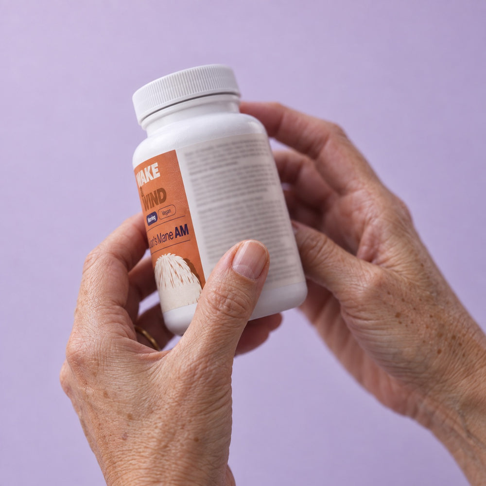 Hands turning a Lion's Mane AM bottle to read the Supplement Facts on the back label